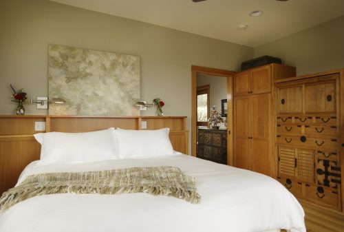 Cozy bedroom featuring a white bed, wooden furniture, and soft lighting, with decorative wall art and plants.