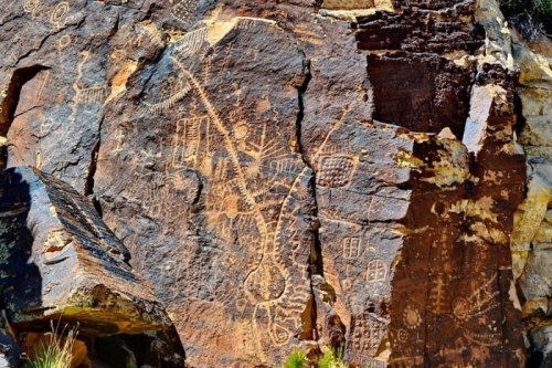 Ancient rock art featuring intricate petroglyphs carved into a rugged stone surface.