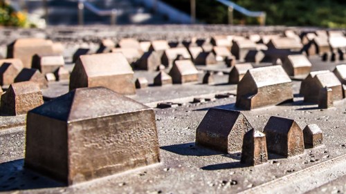 A close-up of a bronze relief map featuring miniature houses and buildings, showcasing a detailed urban landscape.