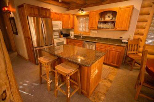 Cozy kitchen with wooden cabinets, granite island, and stainless steel appliances, featuring a warm, rustic design.