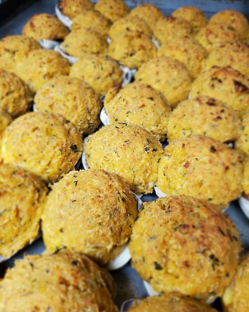A tray filled with golden-brown, baked savory muffins, topped with a crispy crust and herbs.