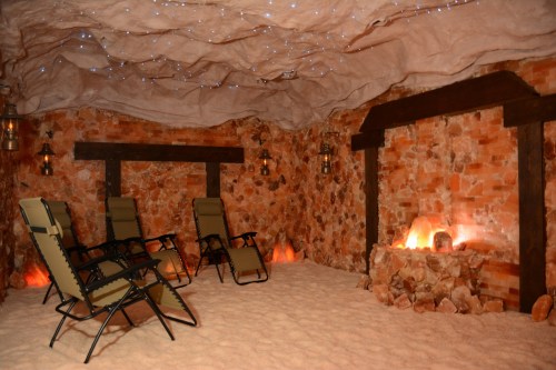 A cozy salt room with reclining chairs, brick walls, and soft lighting, creating a relaxing atmosphere.