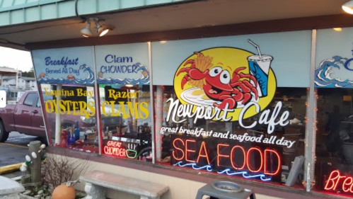 A restaurant window displays a colorful sign for Newport Cafe, featuring seafood and breakfast offerings.