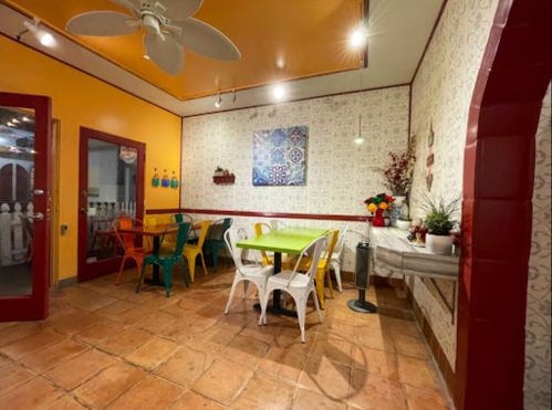 Colorful dining area with a green table, metal chairs, and decorative wall art in a cozy, inviting atmosphere.