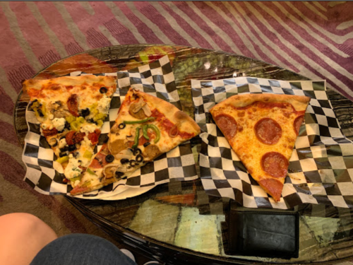 Three slices of pizza on checkered paper: one with pepperoni, one with vegetables, and one with a mix of toppings.
