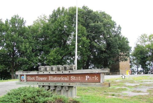 Sign for Shot Tower Historical State Park with a stone tower and trees in the background.