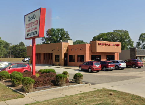 Exterior of Nick's Country Oven restaurant, featuring a red sign and parked cars in a suburban setting.