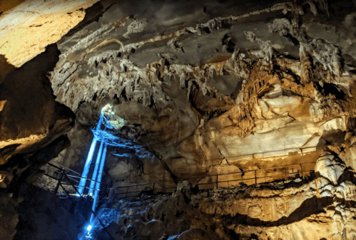 A cave interior with dramatic rock formations and beams of light illuminating the space.