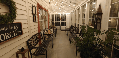 A cozy porch with string lights, benches, and plants, creating a warm and inviting atmosphere.