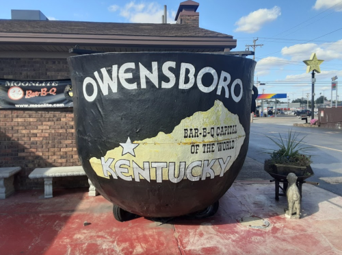 A large black bowl-shaped sign reading "Owensboro, Bar-B-Q Capital of the World, Kentucky" outside a restaurant.
