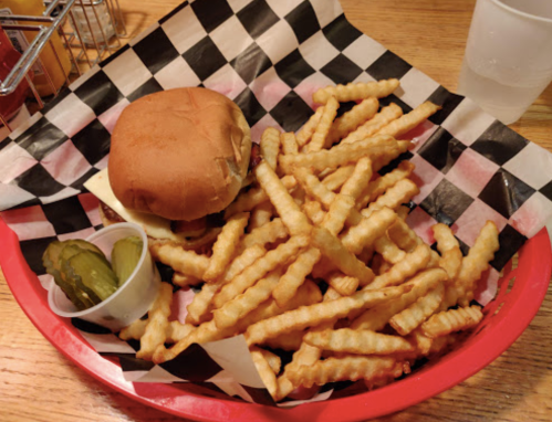 A basket with a sandwich, crinkle-cut fries, and pickles on a checkered paper liner.