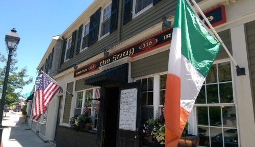 Exterior of a restaurant called "the Spug," featuring American and Irish flags, with a welcoming entrance.