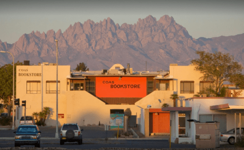 A bookstore with a mountain backdrop, featuring a clear sky and parked cars in the foreground.