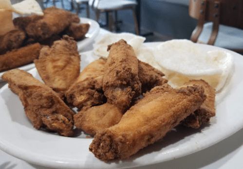 A plate of crispy fried chicken wings served with white rice cakes.
