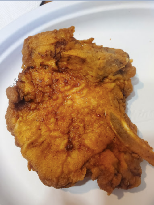 A large, golden-brown fried chicken piece on a white plate.