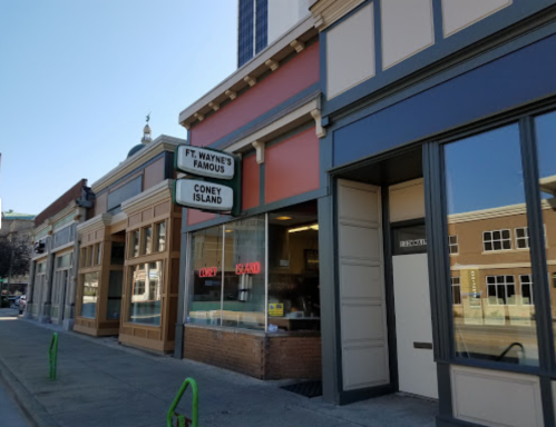 A street view of storefronts, featuring a sign for "Ft. Wayne's Famous Coney Island" with an open sign in the window.