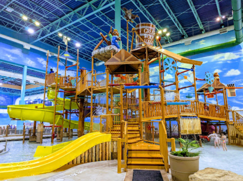 A colorful indoor water park with slides, play structures, and a large water play area.