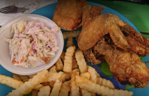 A colorful plate with fried chicken, crinkle-cut fries, and a side of coleslaw.