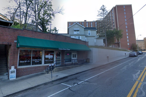 A street view of Union Street Diner with a green awning, surrounded by buildings and trees.