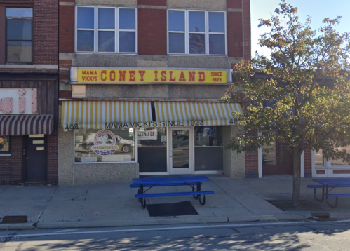 Exterior of Mama Vicki's Coney Island, featuring a yellow awning and a sign with the establishment's name and founding year.