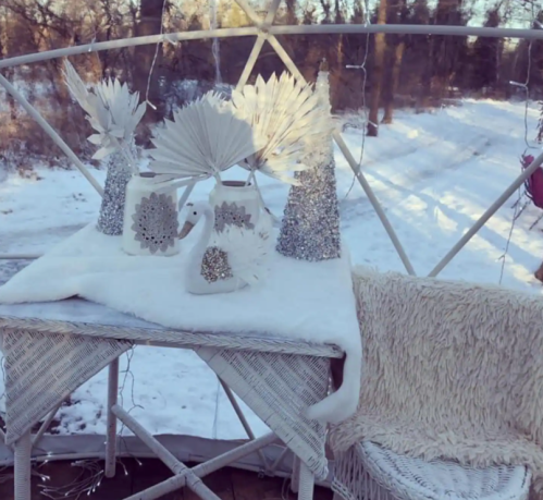 A cozy winter scene featuring white decorations, including trees and a swan, on a table with a snowy background.