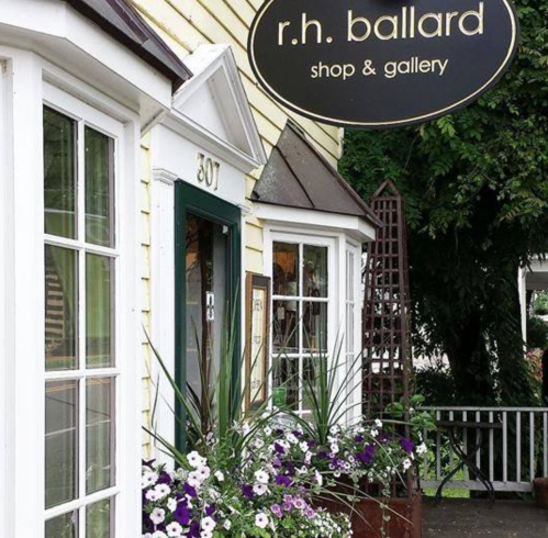 Exterior of a charming shop and gallery, featuring a sign that reads "r.h. ballard" and colorful flower arrangements.