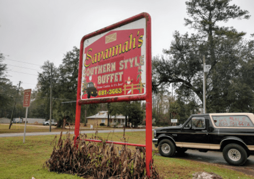 Sign for Savannah's Southern Style Buffet, featuring colorful graphics and contact information, set in a rural area.