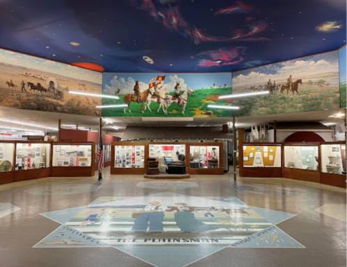 Interior of a museum featuring murals on the ceiling and display cases showcasing historical artifacts.