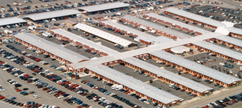 Aerial view of a large parking lot with numerous cars and a series of connected buildings.