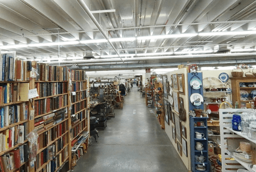 A spacious antique store aisle lined with bookshelves and various vintage items on display.