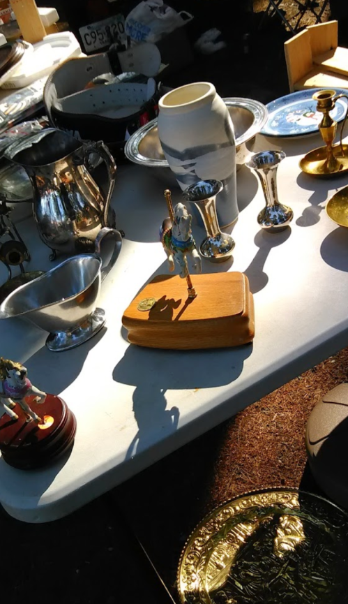 A table covered with various vintage items, including silverware, vases, and decorative figurines.