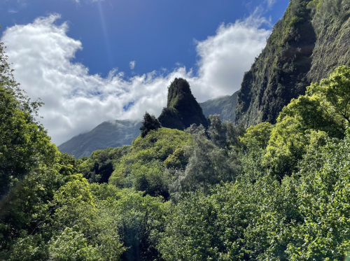 Lush green mountains under a blue sky with fluffy clouds, showcasing a vibrant natural landscape.