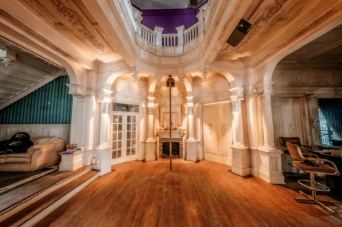 A spacious, elegantly designed room with ornate architecture, wooden floors, and a cozy seating area.