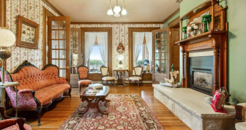 A vintage living room with ornate furniture, a fireplace, and decorative wallpaper, featuring a cozy, inviting atmosphere.