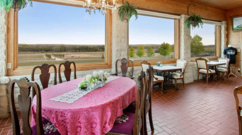 Cozy dining area with a pink tablecloth, large windows, and scenic views of greenery outside.