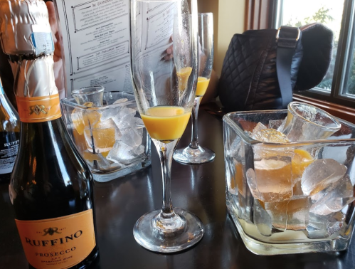 A table setting with a bottle of Ruffino Prosecco, glasses of orange juice, and ice-filled glasses.