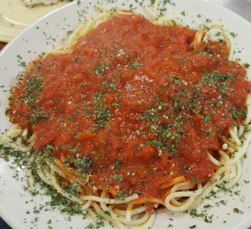 A plate of spaghetti topped with marinara sauce and sprinkled with herbs.
