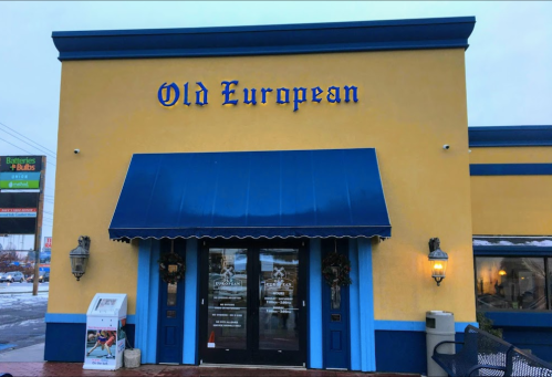 Exterior of a restaurant named "Old European," featuring a blue awning and yellow walls, with decorative elements.