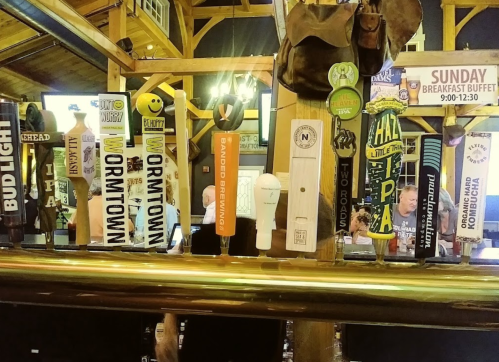 A row of beer taps featuring various brands and styles in a rustic bar setting.