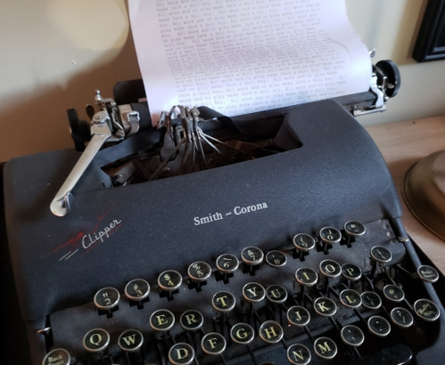 Close-up of a vintage Smith-Corona typewriter with a sheet of typed paper partially visible.