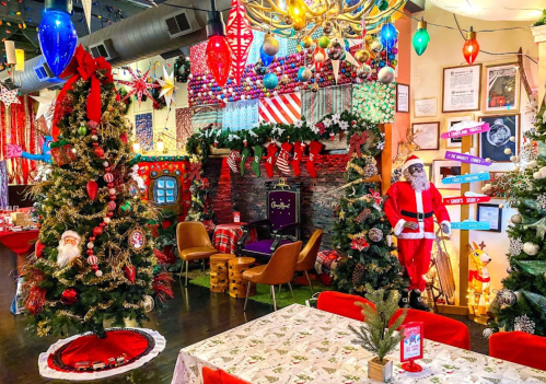 A festive restaurant decorated with Christmas trees, lights, and Santa figures, creating a cheerful holiday atmosphere.