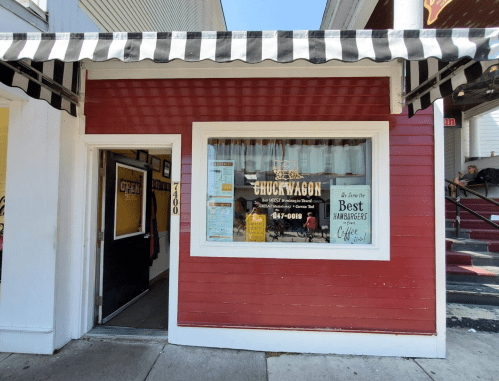 A red storefront with a striped awning, featuring a sign for "Chuck Wagon" and an "Open" sign in the window.
