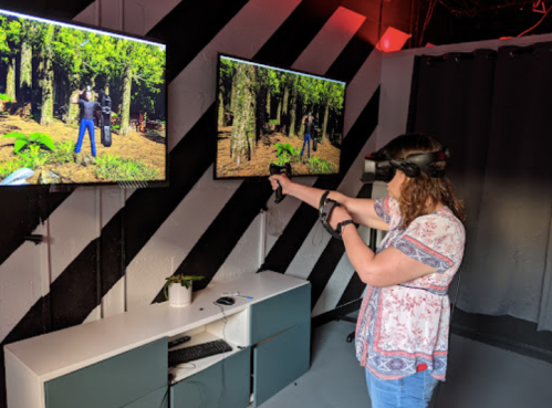 A person wearing a VR headset interacts with virtual screens displaying a forest scene.