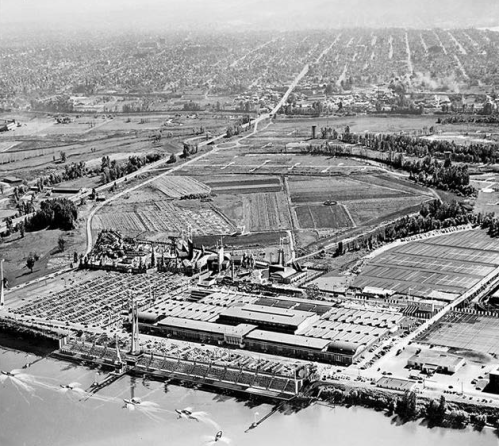 Aerial view of a large industrial complex surrounded by fields and roads, captured in black and white.