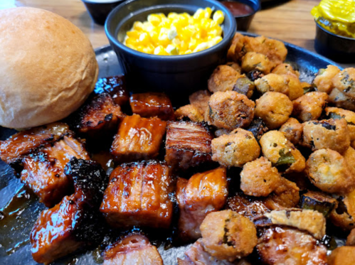 A plate of barbecue with glazed meat, fried okra, macaroni and cheese, and a roll.
