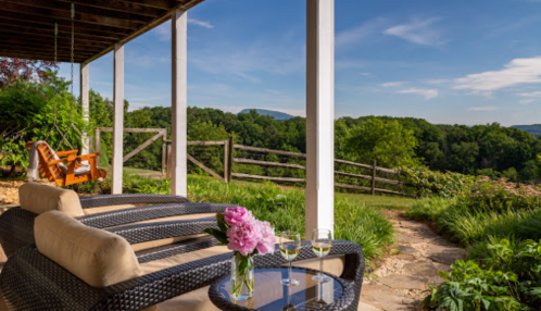 A serene outdoor patio with lounge chairs, a table with drinks, and a view of lush greenery and mountains.