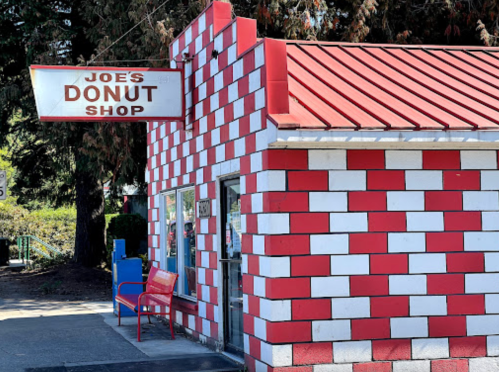 A colorful donut shop with a red and white checkered exterior and a sign that reads "Joe's Donut Shop."