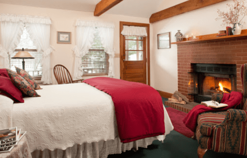 Cozy bedroom with a bed, fireplace, and rustic decor, featuring warm colors and natural light.