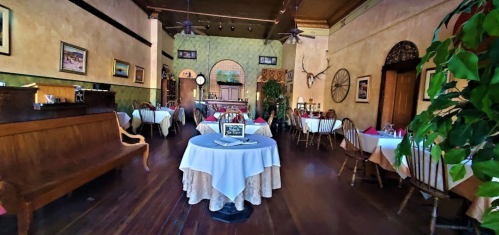 Cozy restaurant interior with wooden furniture, round tables, and decorative plants, creating an inviting atmosphere.