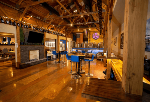 Interior of a rustic restaurant with wooden beams, a bar area, and an American flag displayed on the wall.